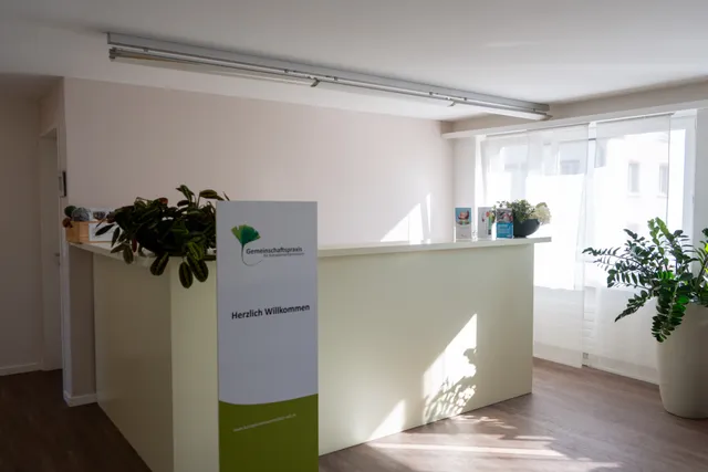 Empfangsbereich der Gemeinschaftspraxis mit Pflanzen und hellem Tresen
